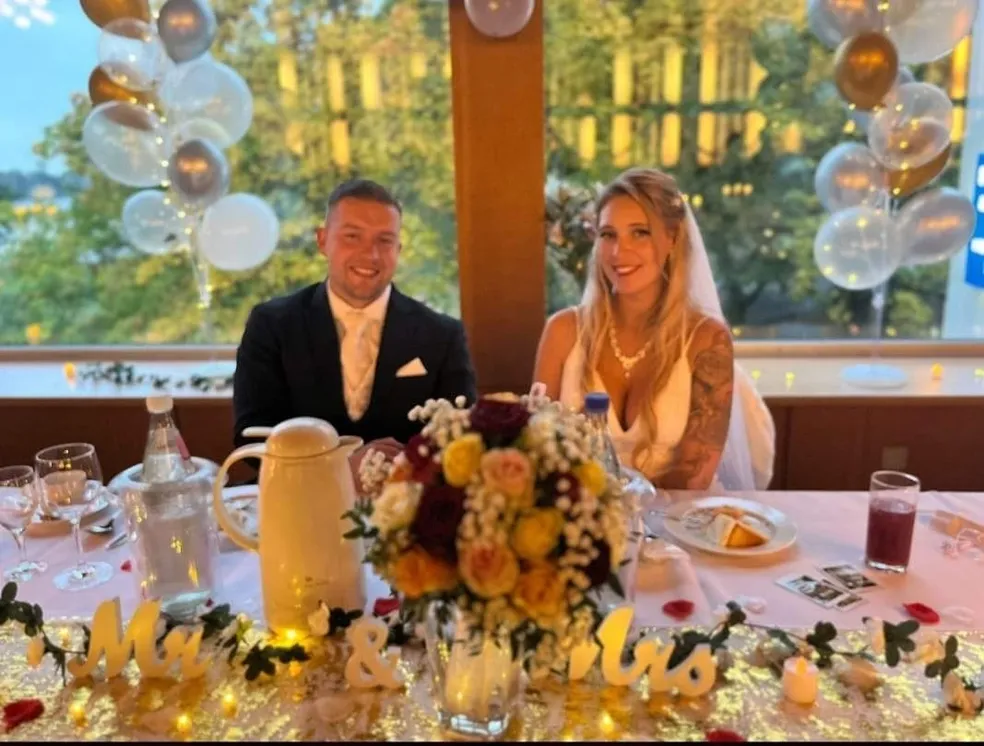 Glückliche Braut und Bräutigam bei ihrem Hochzeitsempfang, lächeln in die Kamera.