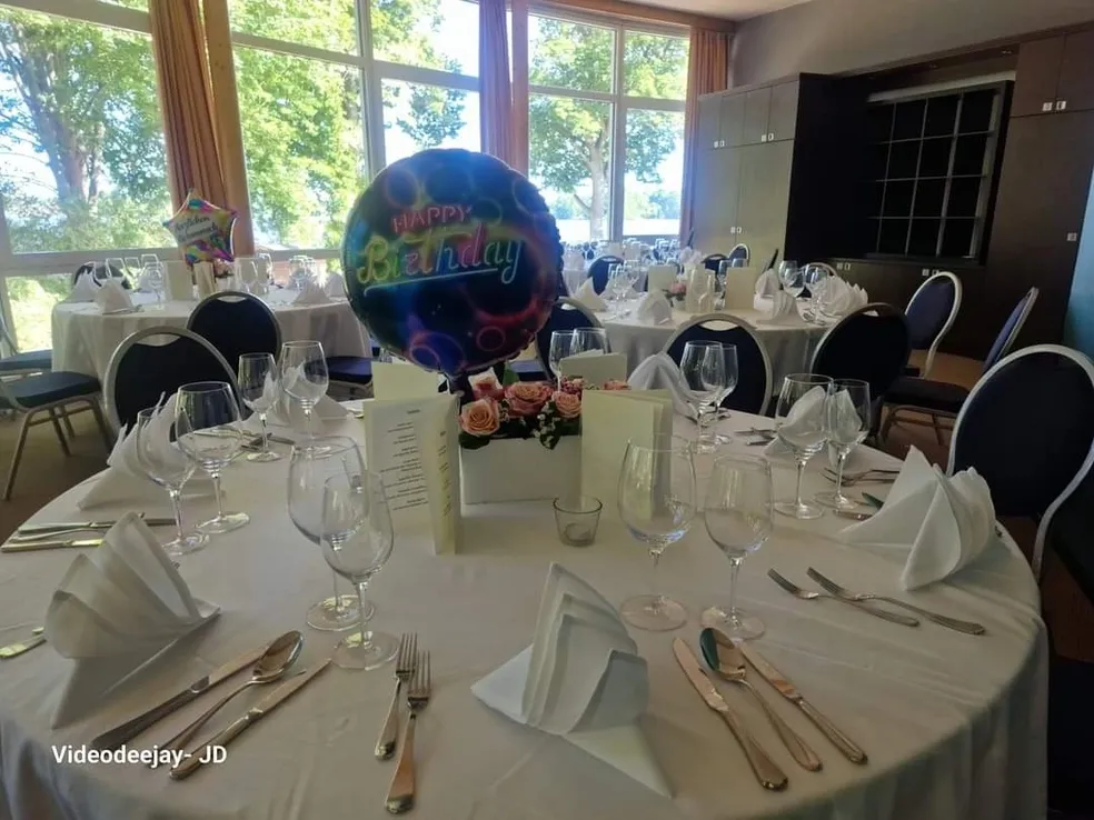 Tischdekoration für die Geburtstagsparty mit „Happy Birthday“-Ballons, Blumen und Besteck.