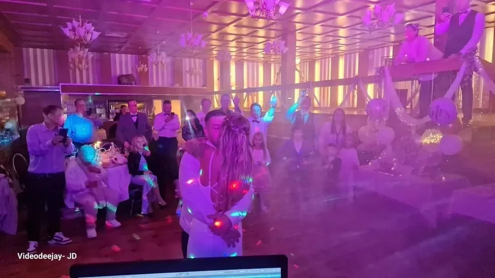 Braut und Bräutigam tanzen auf der Hochzeitsfeier, umgeben von feiernden Gästen.